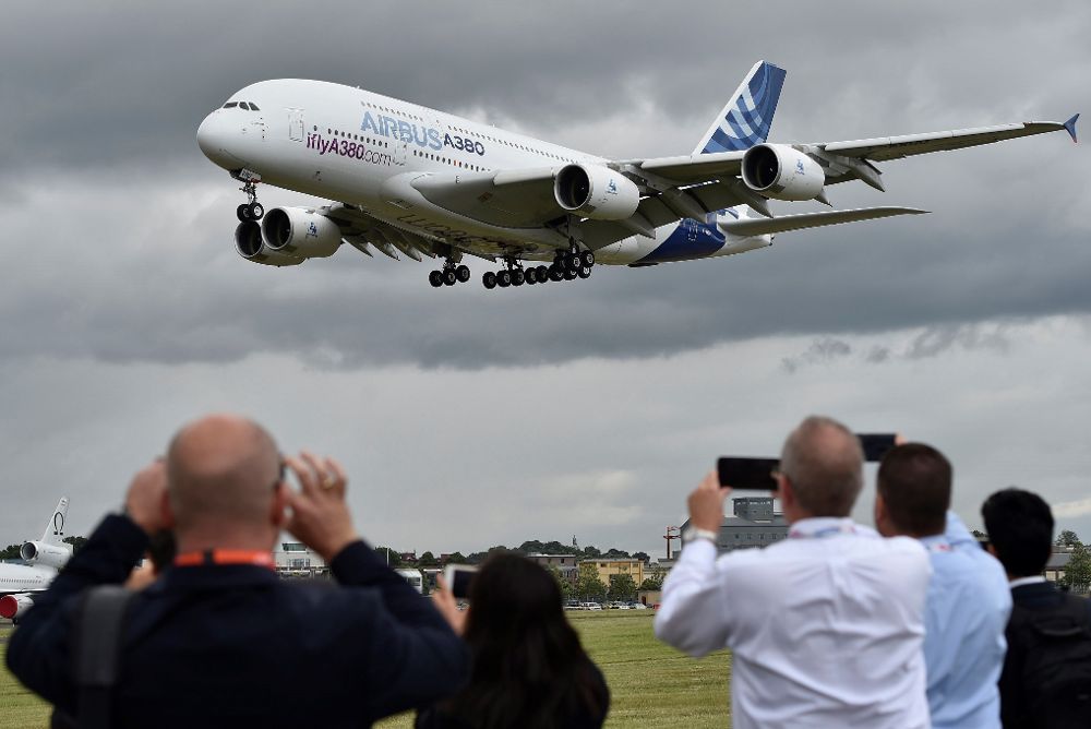 Fotografía de archivo que muestra a un grupo de personas mientras fotografían un Airbus A380 durante una demostración en Farnborough, Reino Unido.