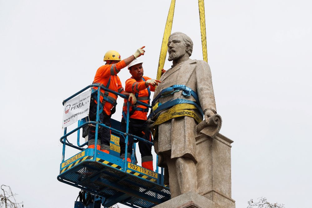 Operarios del Ayuntamiento de Barcelona retiran el monumento en memoria de Antonio López.