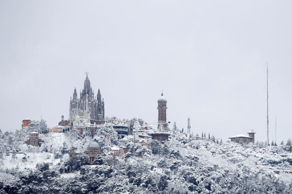 Vista de la montaña del Tibidabo, vista desde Barcelona, que hoy ha amanecido cubierto de nieve, en una jornada en la que la llegada de la primavera coincide con un frente que dejará nieve en cotas de hasta 400 metros y lluvia en el resto.