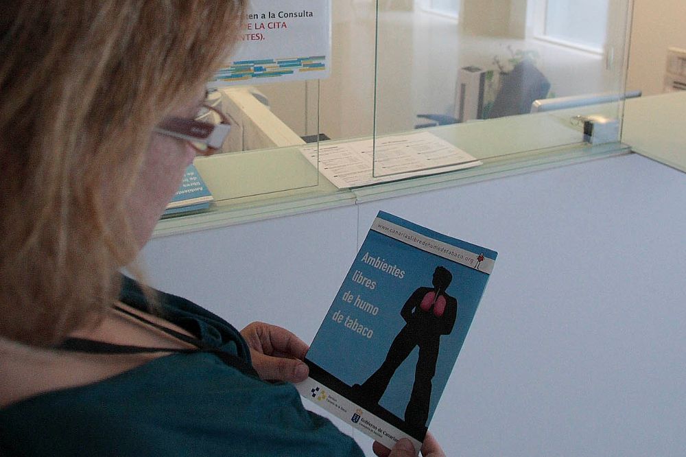Una mujer mira un folleto informativo sobre la enfermedad en un centro sanitario.