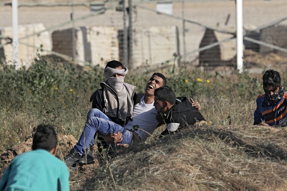 Manifestantes palestinos llevan en brazos a un compañero herido durante los choques con las tropas israelíes desplegadas en la frontera entre Israel y Gaza.