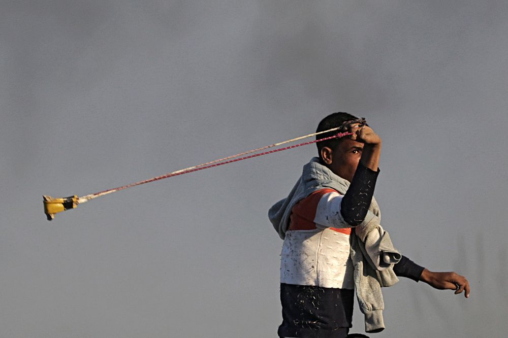 Un manifestante palestino lanza piedras con una honda contra las posiciones israelíes en la frontera entre Israel y la franja de Gaza.