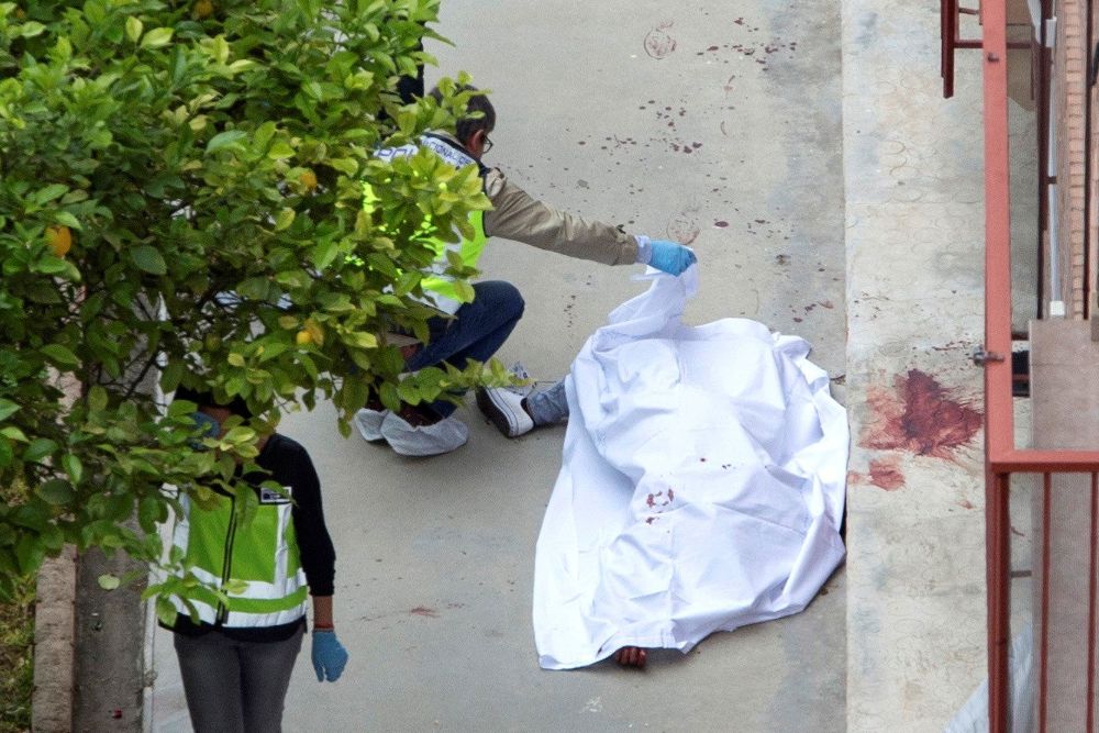 Agentes de la policía nacional examinan el cuerpo de la mujer asesinada.