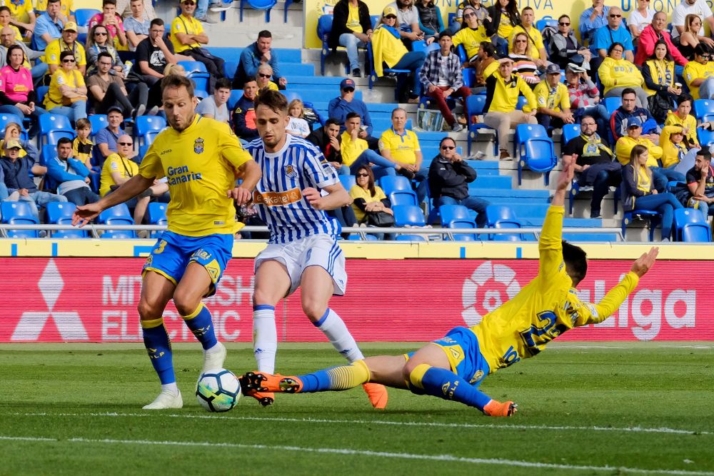 Los defensas Dani Castellano (i) y Ximo Navarro (d), de Las Palmas, disputan el balón al delantero de la Real Sociedad Adnan Januzaj (c).