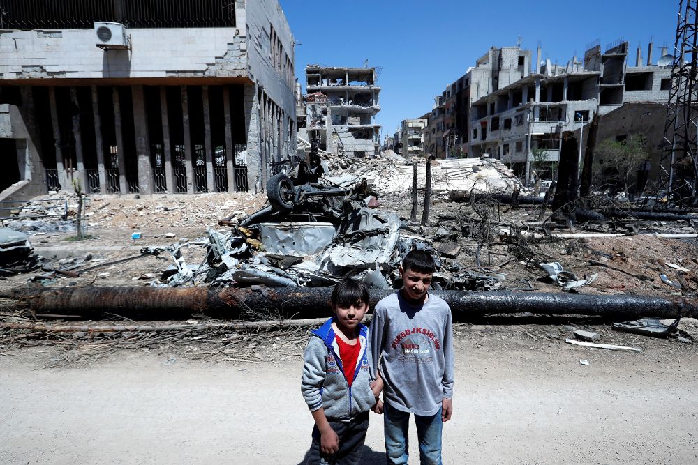 Dos niños caminan por una calle en ruinas en Duma, Guta Oriental, cerca de Damasco (Siria) hoy, 16 de abril de 2018.