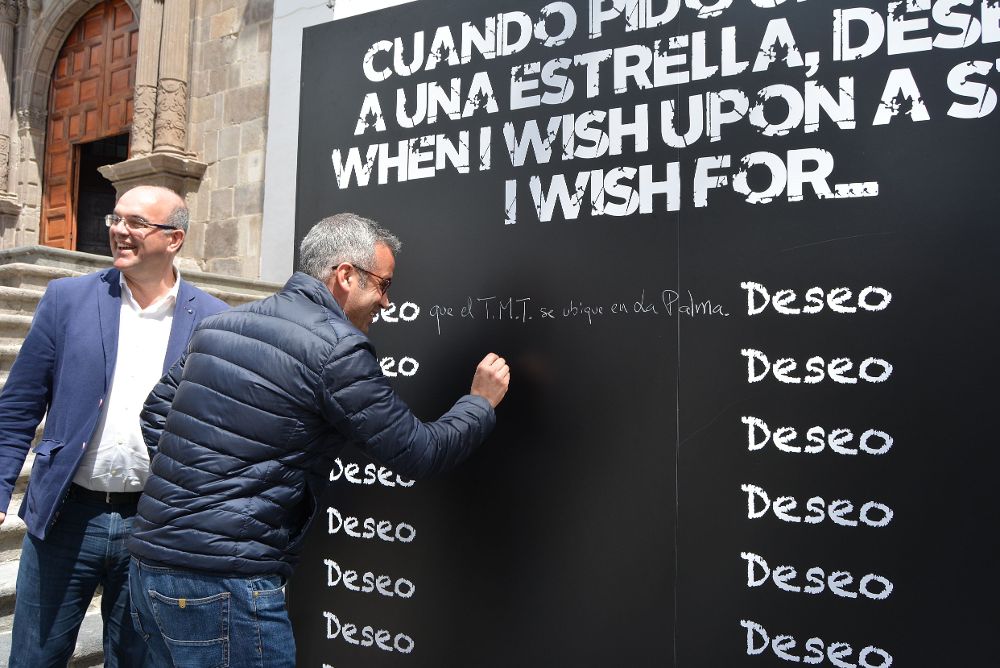 El presidente del Cabildo palmero, Anselmo Pestana, con un ciudadano ante la pizarra instalada en la plaza de España de Santa Cruz donde se anima a escribir el deseo de que el telescopio vaya a la isla.