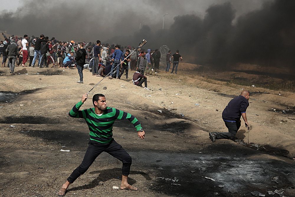 Un joven lanza una piedra con una honda durante los enfrentamientos contra el ejército israelí cerca de la frontera de Palestina con Israel, en Gaza.