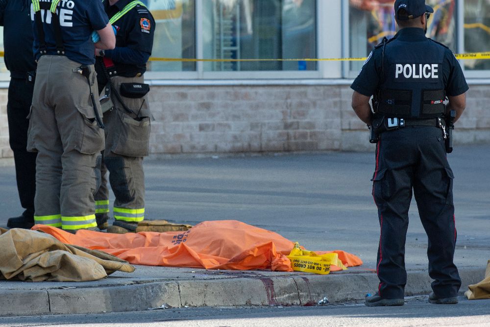 Un oficial de la policía de Toronto vigila junto al cuerpo cubierto de una de las personas fallecidas en el atropello.