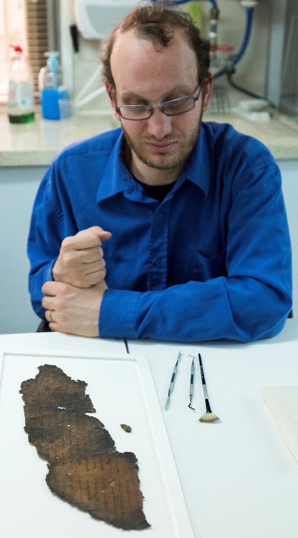 Un conservador muestra un fragmento de pergamino encontrado.