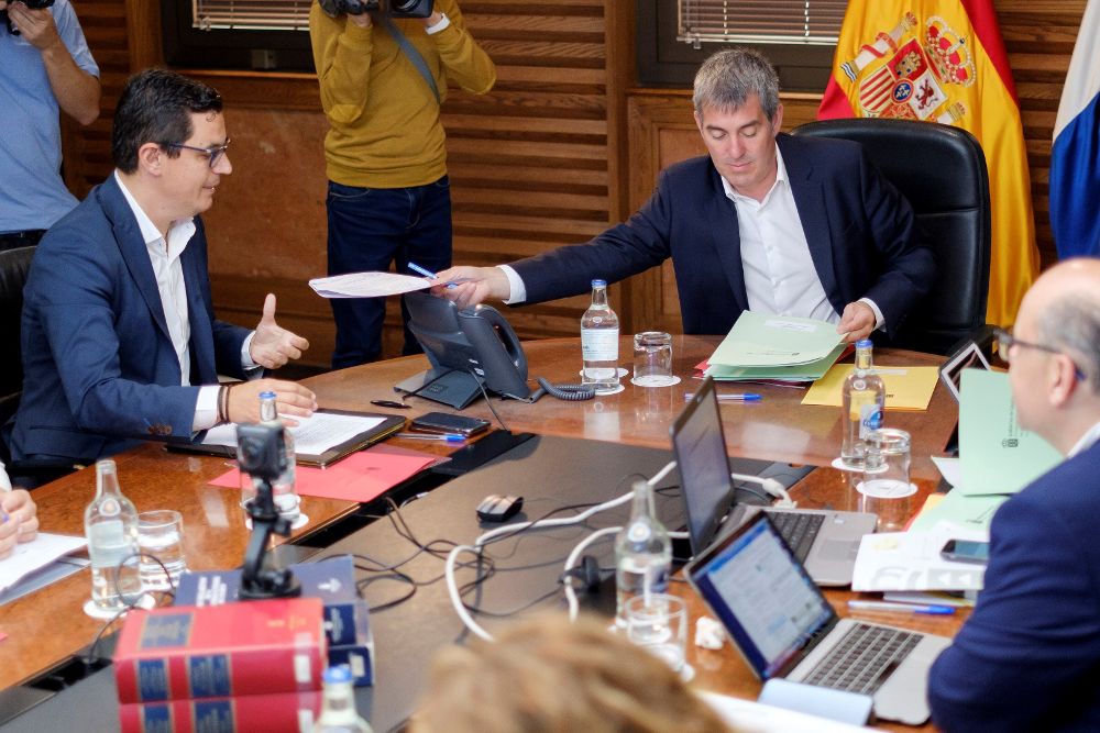 El presidente de Canarias, Fernando Clavijo (d), entrega unos documentos al vicepresidente y consejero de Obras Públicas, Pablo Rodríguez (i), al comienzo de la reunión semanal del Consejo de Gobierno.