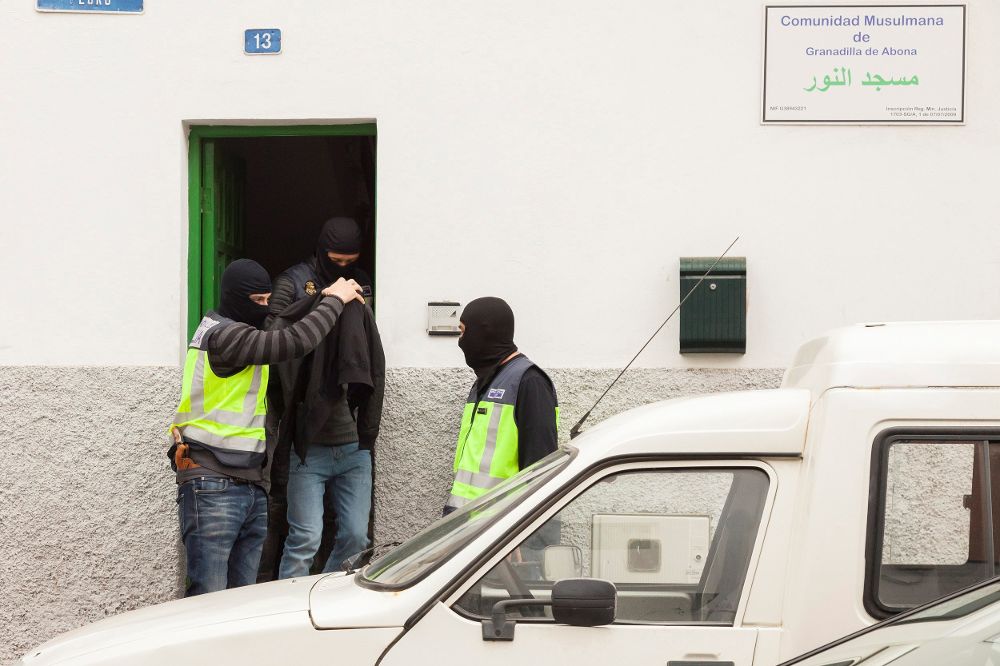Efectivos de la Policía Nacional sacan del edificio de la Comunidad Musulmana en San Isidro, municipio de Granadilla de Abona, a uno de los tres ciudadanos marroquíes detenidos ayer, lunes.