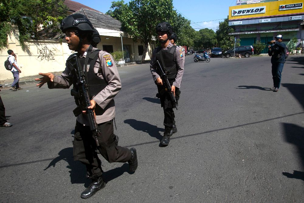 Policías indonesios aseguran el perímetro de la zona donde estalló una bomba, junto al cuartel de los agentes en la ciudad de Surabaya, al este de Java.