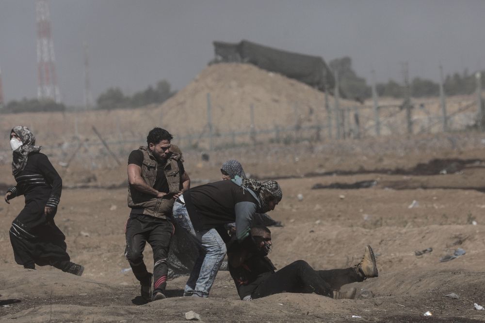 Manifestantes palestinos tratan de ayudar a un camarada herido durante los enfrentamientos.