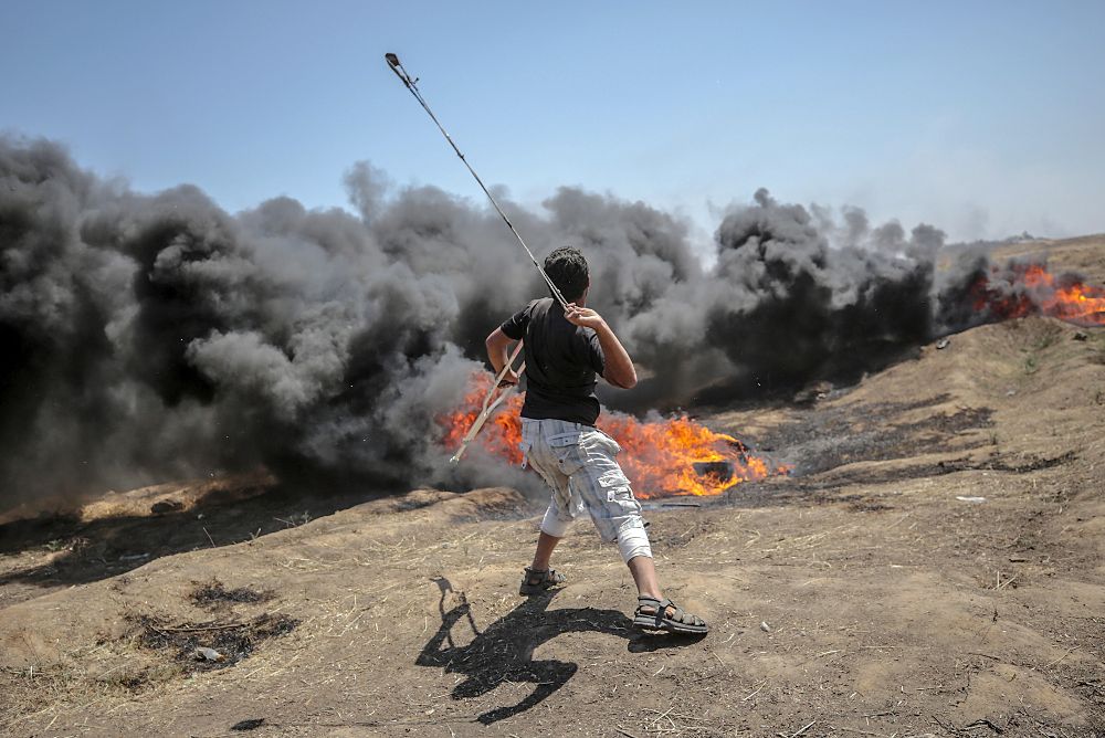 Un palestino lanza piedras hacia soldados israelíes durante la protesta de ayer, lunes, que acabó en matanza.