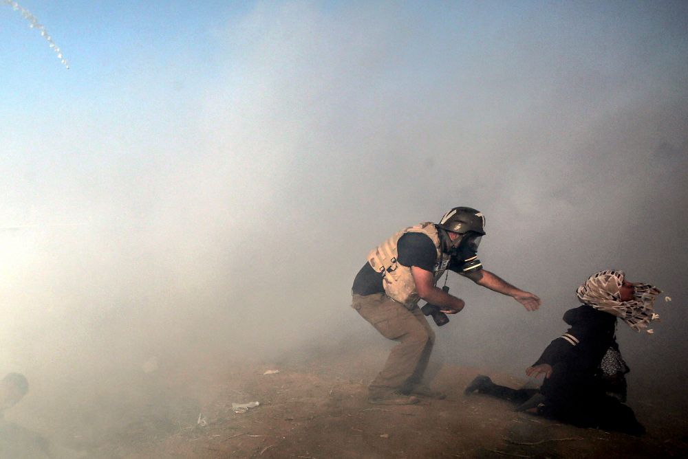 Un fotoperiodista trata de ayudar a una manifestante después de que los israelíes lanzaran gases lacrimógenos.
