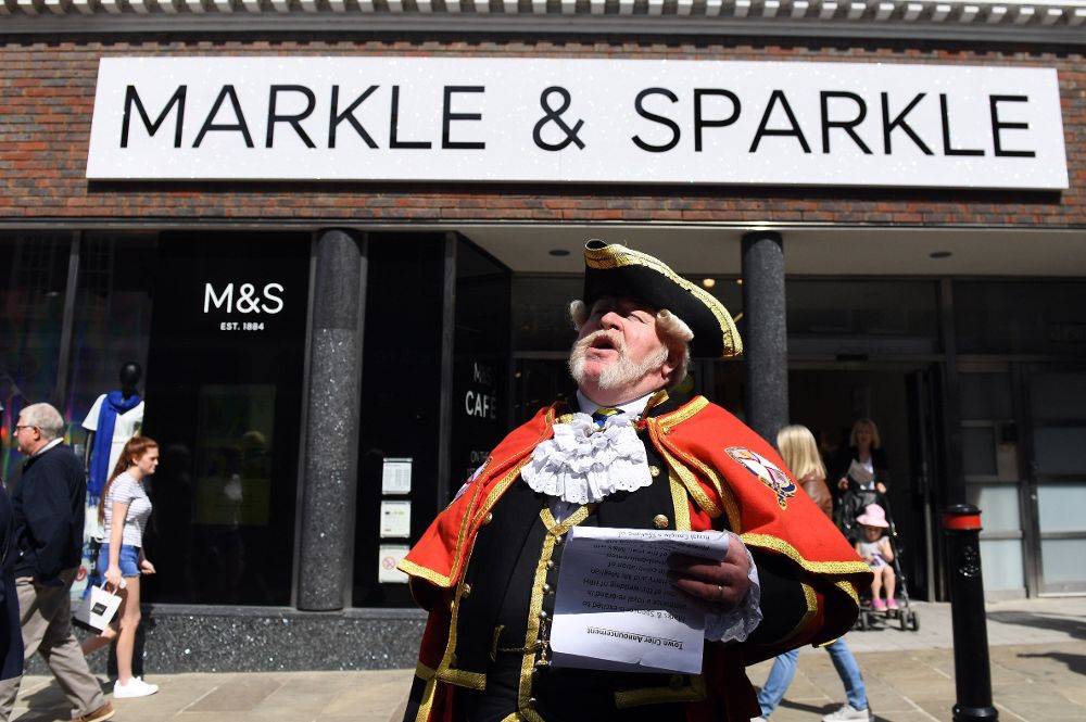 Un pregonero ante una tienda de Marks & Spencer renombrada "Markle and Sparkle" un día antes de la boda del príncipe Enrique y su prometida Meghan Markle en Windsor.