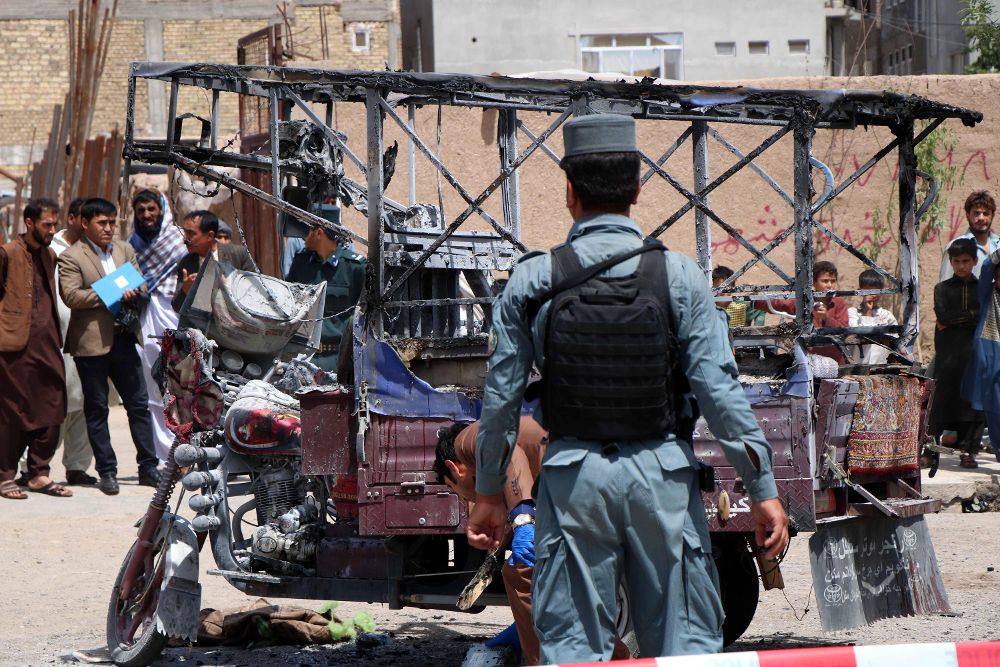 Varios policías inspeccionan el lugar de un atentado contra un vehículo que transportaba a miembros de la minoría Hazara en Herat (Afganistán).