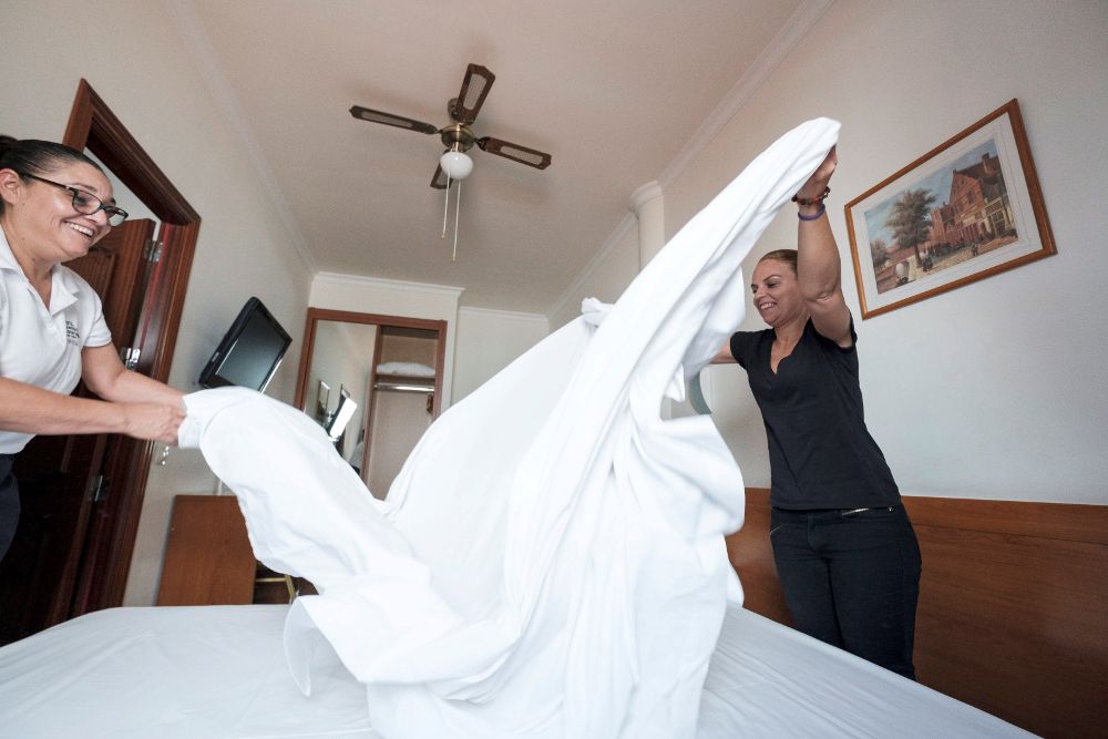 La secretaria general de Podemos en Canarias, Noemí Santana (i), hace una cama durante la mañana que ha pasado trabajando como camarera de piso, también llamadas "kelly", en un hotel de Gran Canaria.