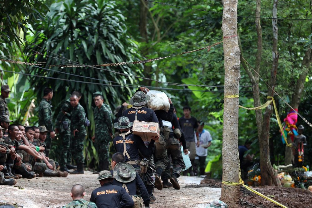 Varios soldados tailandeses llevan provisiones mientras continúan las labores de rescate de los doce niños y su monitor.