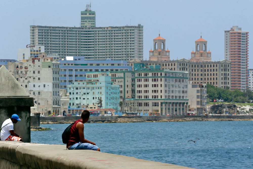 Dos hombres observan la vista mientras descansan sentados en el Malecón de La Habana (Cuba).