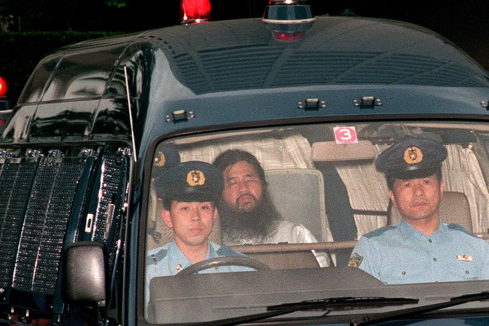 Foto de archivo del 16 de junio de 1995, que muestra al fundador del culto Aum Shinrikyo, Shoko Asahara (c), con nombre de nacimiento Chizuo Matsumoto, quien es escoltado por la policía al Departamento de Policía Metropolitana de Tokio.