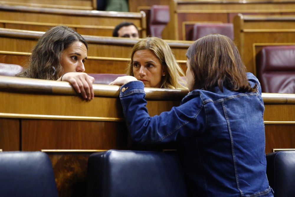 La vicesecretaria general del PSOE, Adriana Lastra (de espaldas), conversa con las diputadas de Unidos Podemos, Ione Belarra (d) y Noelia Vera.