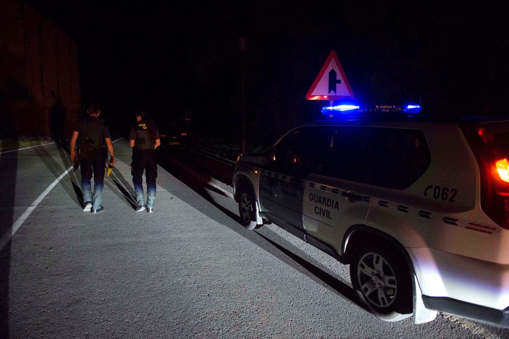 Dos agentes de la Guardia Civil cortan la carretera que da acceso al lugar en el que el hombre estaba atrincherado.