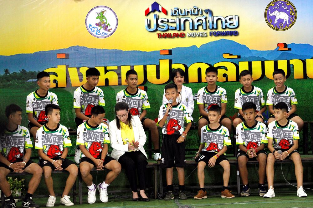 Los doce niños y su entrenador rescatados del interior de una cueva en el norte de Tailandia se dirigen a los medios durante su primera aparición pública.