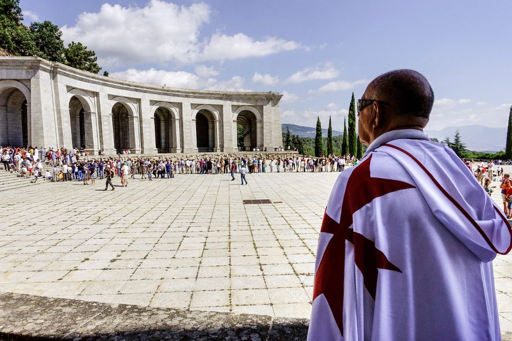 Un hombre ataviado con una capa blanca y la característica cruz roja de los caballeros del Temple observa la concentración en el Valle de los Caídos de quienes se oponen a exhumar los restos de Franco.
