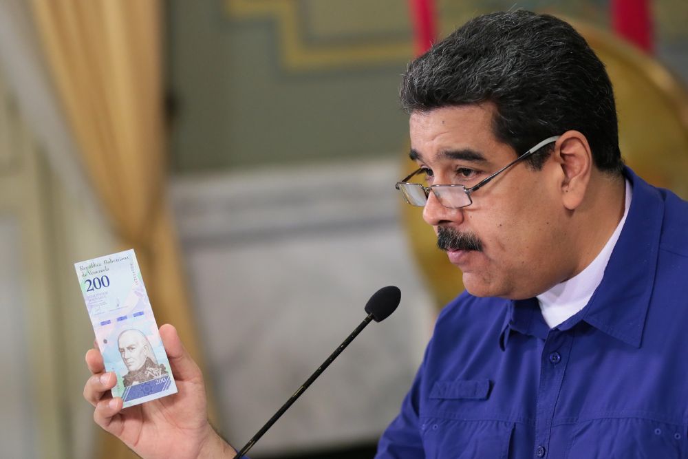Fotografía cedida por la Oficina de Prensa de Miraflores que muestra al presidente de Venezuela, Nicolás Maduro, mientras muestra nuevos billetes.