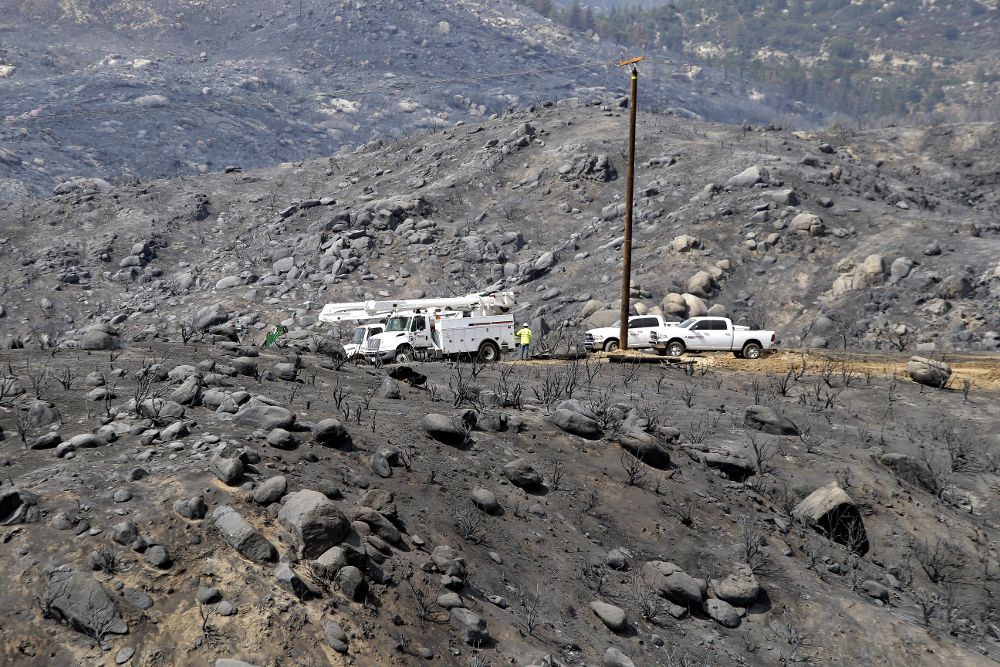 Operarios del dispoisitivo de extinción en medio de la devastación causada por el fuego en en Mountain Center, California.