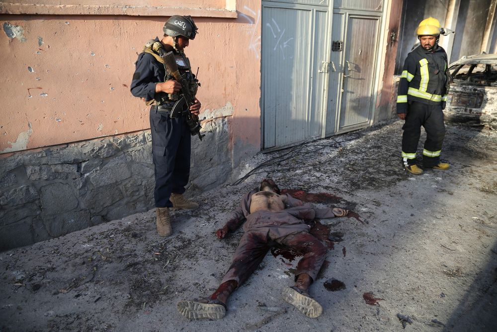 Oficiales de seguridad observan el cuerpo sin vida de un militante en la escena del ataque a la sede provincial del Ministerio afgano de Refugiados, en la ciudad de Jalalabad.