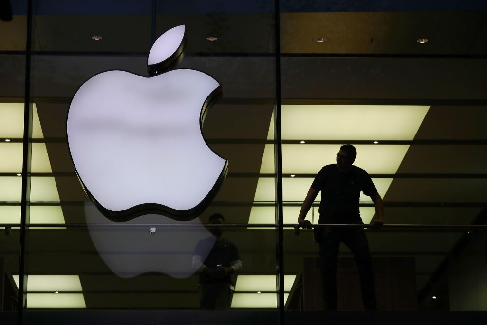 Fotografía de archivo muestra a un hombre cerca de un logotipo de Apple.