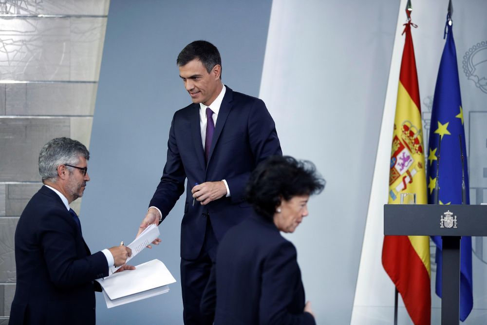 El presidente del Ejecutivo, Pedro Sánchez, entrega sus notas al secretario de Estado de Comunicación, Miguel Ángel Oliver, tras su comparecencia.