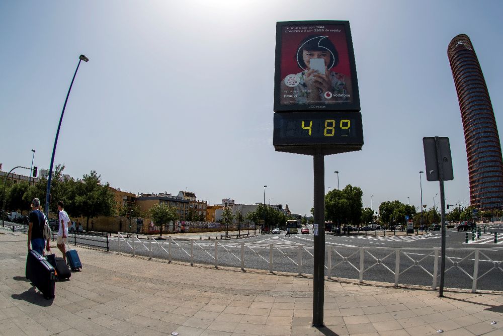La ola de calor está castigando casi toda la Península. En la foto, turistas pasan junto a un termómetro de Sevilla que marca 48ºC.