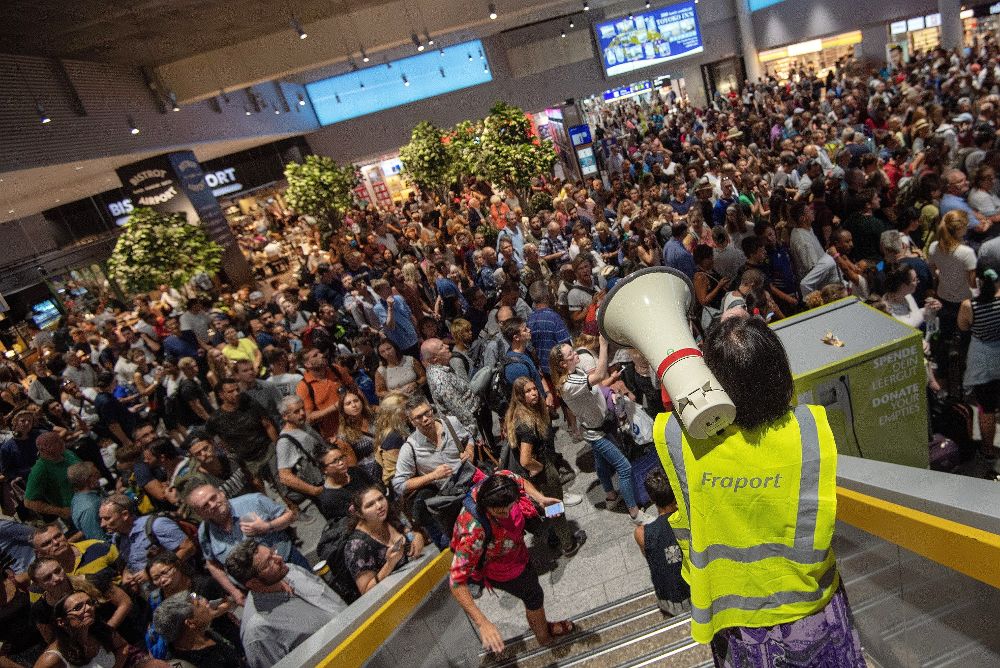 Personal del aeropuerto informa a pasajeros y visitantes mientras esperan a que se termine la evacuación en el aeropuerto de Fráncfort.