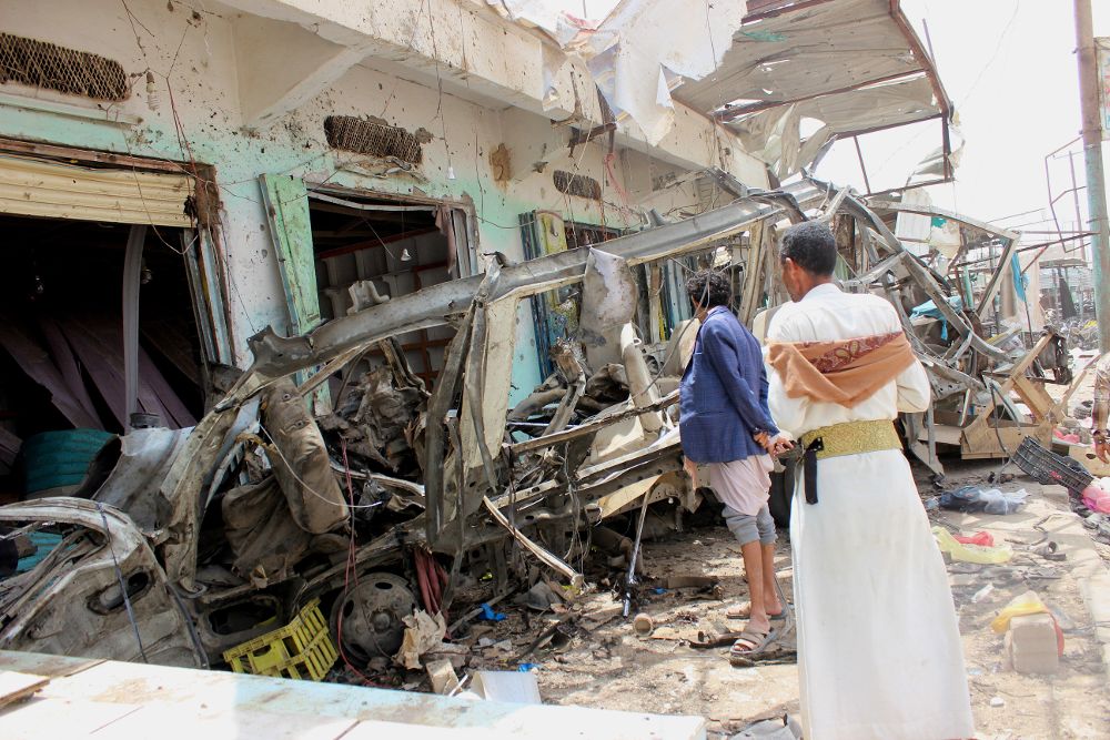 Varios hombres inspeccionan la escena de un ataque aéreo perpetrado por la coalición lidera por Arabia Saudí, un día después del bombardeo a un autobús con niños que causó 50 muertos y 77 heridos, en Sadaa (Yemen).