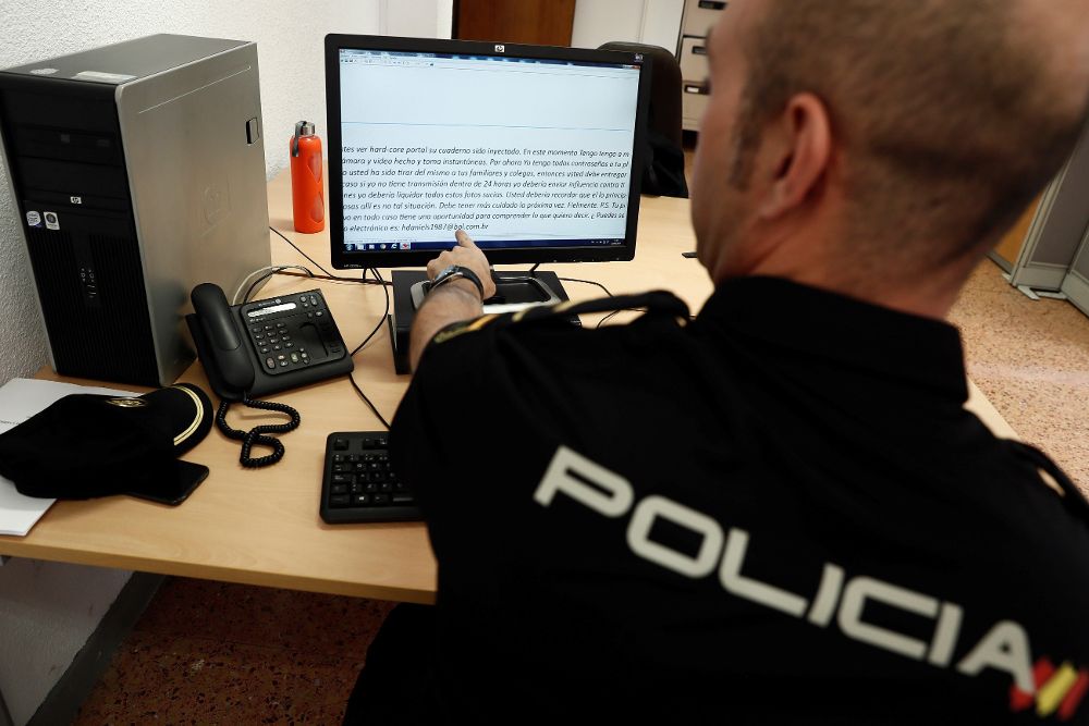 Un agente de la Policía Nacional muestra un mensaje de "sextorsión", el chantaje por internet que pide dinero a usuarios a cambio de no revelar que entran en páginas porno.