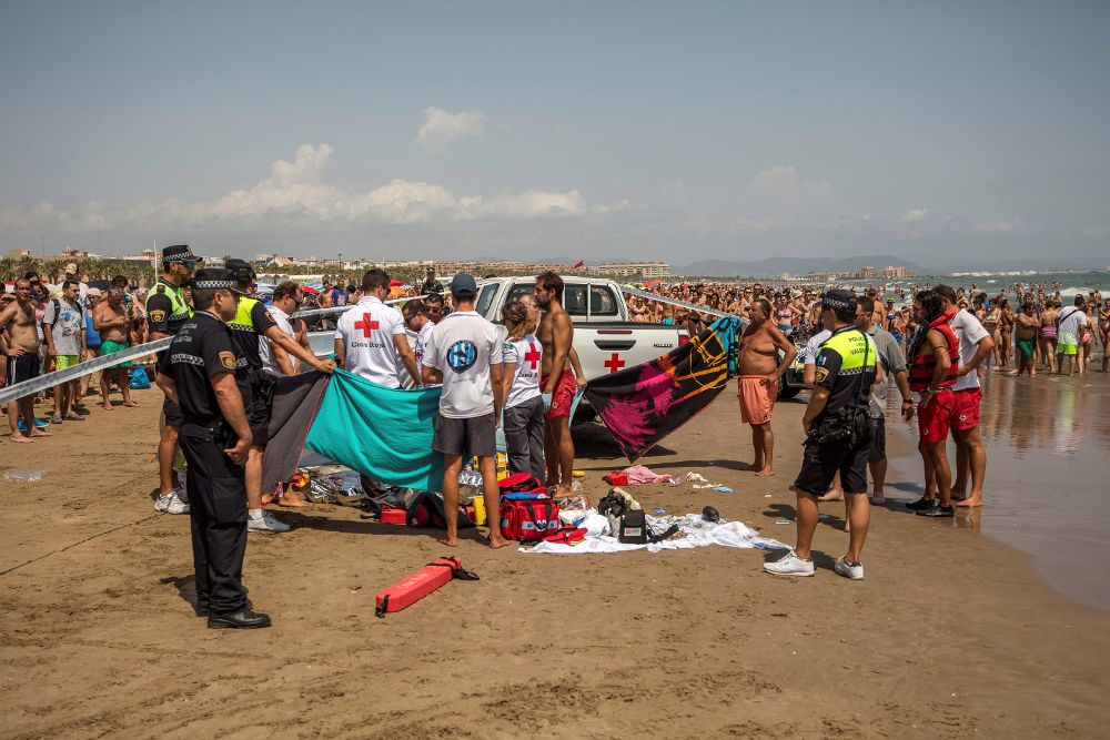 Miembros de la Cruz Roja, junto al cuerpo de un hombre ahogado el día 11 en aguas de la playa de la Malvarrosa, en Valencia. 