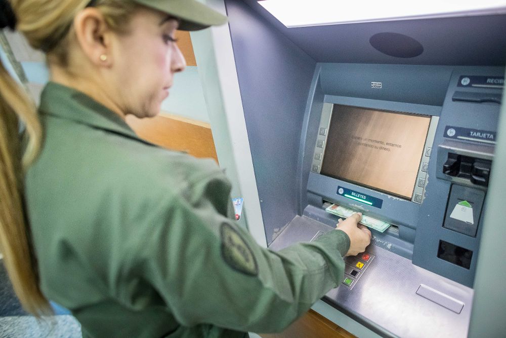 Una militar venezolana retira dinero del nuevo cono monetario en un cajero automático del Banco de las Fuerzas Armadas Bolivarianas (BANFANB) hoy, 20 de agosto. 