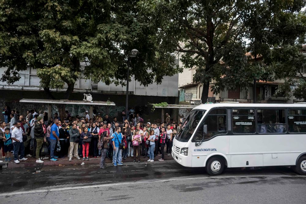 Un grupo de personas aguardan por un bus hoy, martes, en Caracas. Partidos opositores convocan a un paro para rechazar las medidas económicas del presidente Nicolás Maduro.