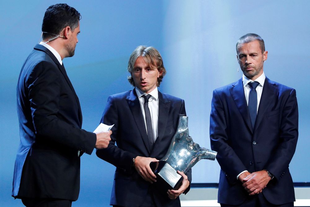 El futbolista croata del Real Madrid Luka Modric (c) recibe el trofeo al mejor jugador de la última temporada de manos del presidente de la UEFA, Aleksander Ceferin (dcha).