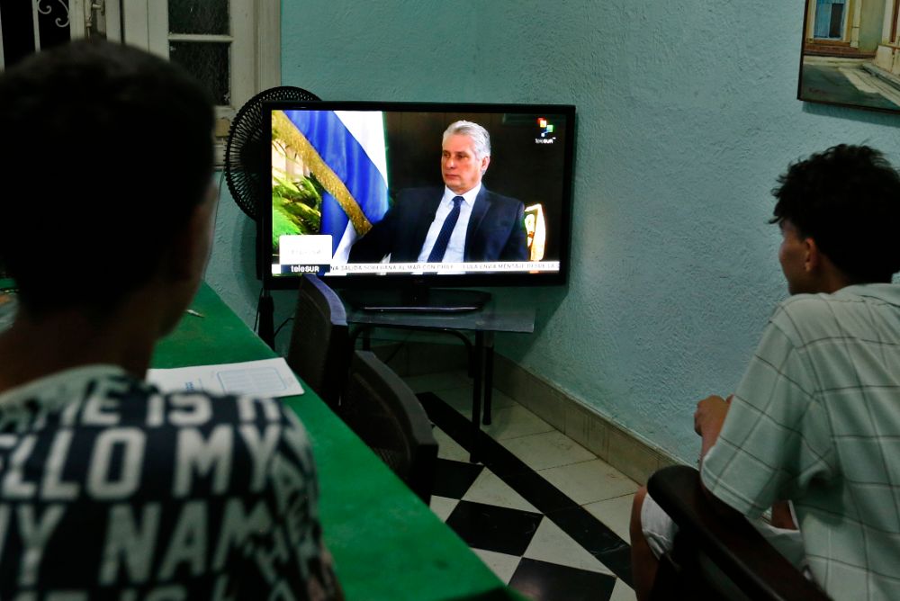 Dos jóvenes ven la entrevista al presidente cubano, Miguel Diaz-Canel, de la cadena de televisión TeleSur, transmitida ayer, domingo.