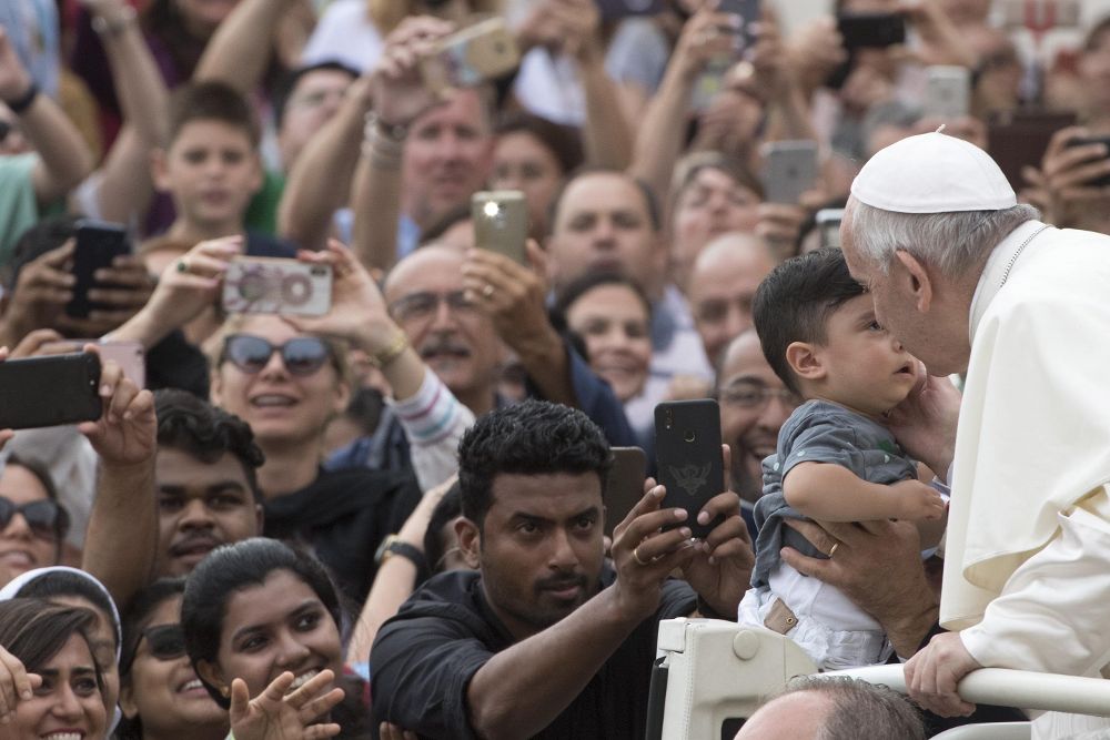 El papa Francisco besa a un niño durante su tradicional audiencia general celebrada en la Plaza de San Pedro.