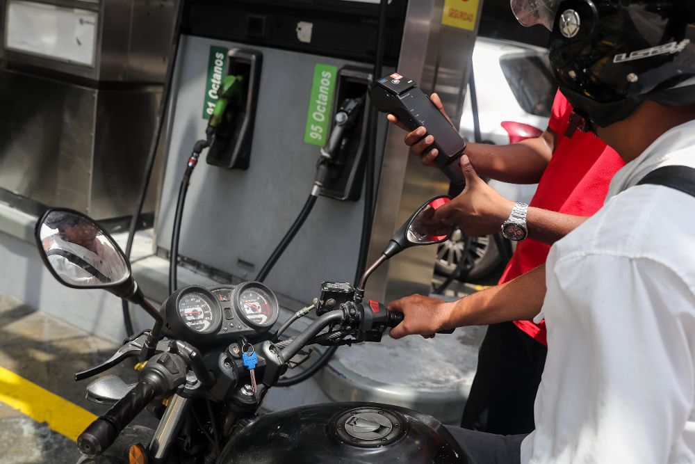Un trabajador de Petróleos de Venezuela explica a un conductor el nuevo método de pago de la gasolina.