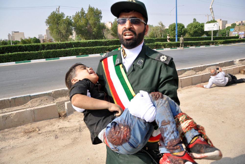 Un soldado iraní carga en brazos con un niño que resultó herido en el atentado terrorista.