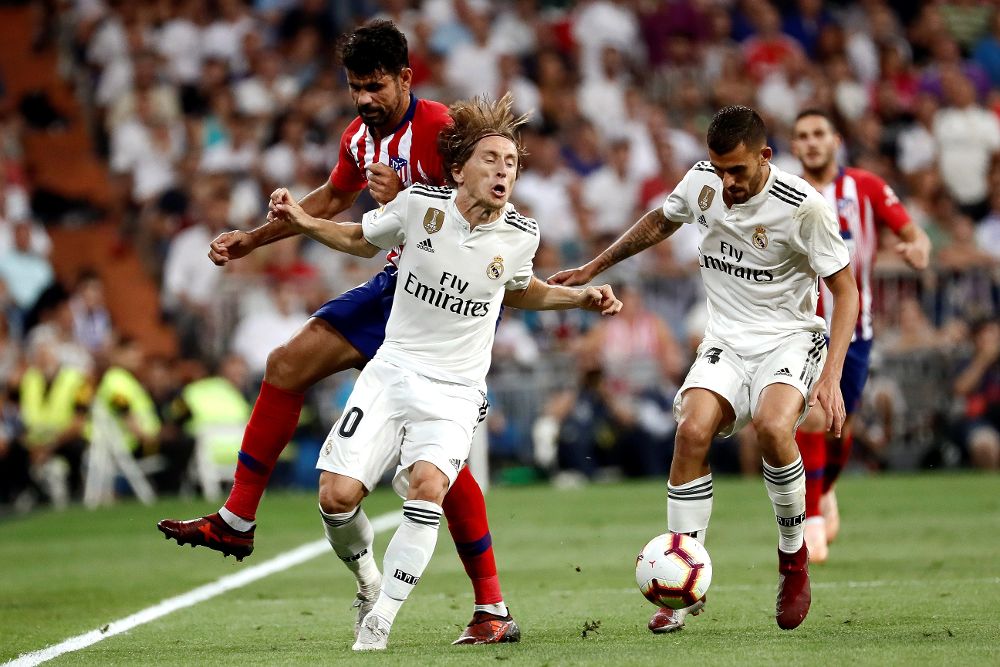 Luka Modric (2i) y Dani Ceballos, del Real Madrid, protegen el balón ante el delantero hispano-brasileño del Atlético de Madrid, Diego Costa.