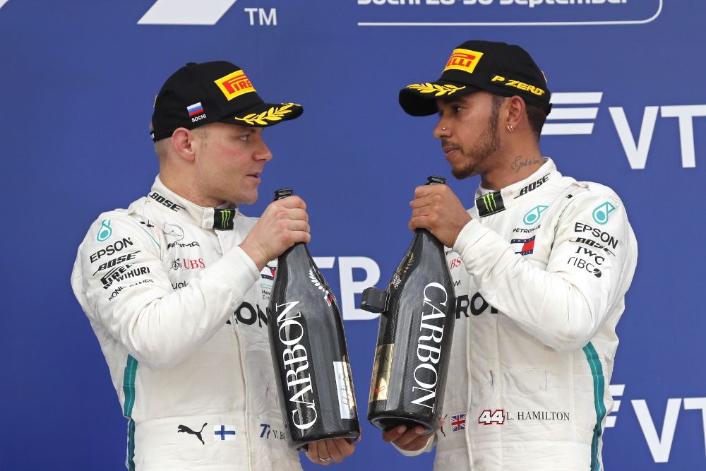 Lewis Hamilton (d) comenta algo en el podio con su compañero del equipo Mercedes AMG Valtteri Bottas.