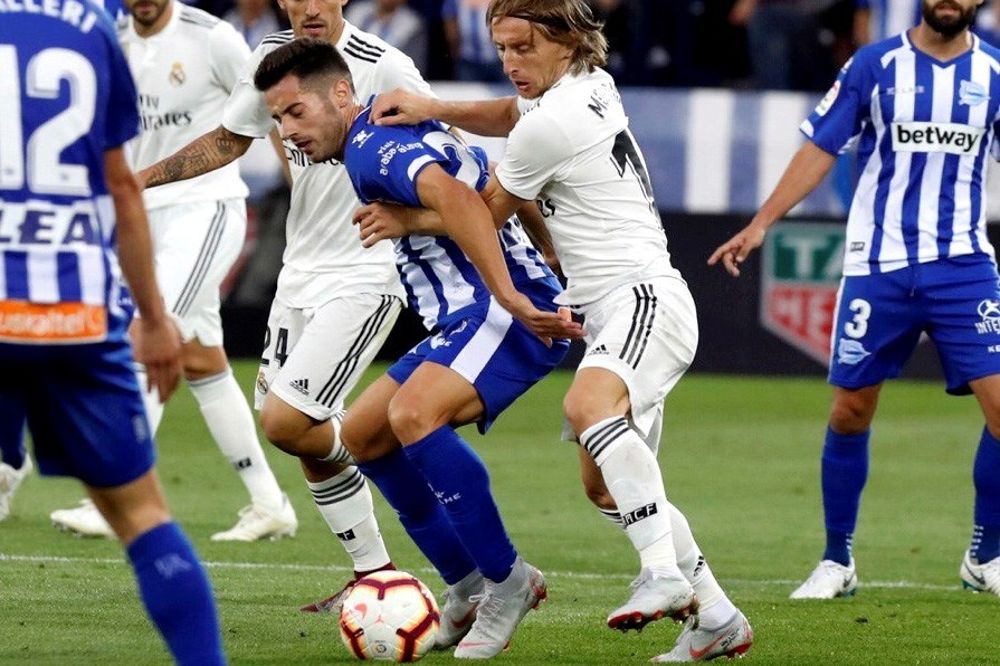 El centrocampista del Real Madrid Luka Modric (d), lucha por el balón detrás de Jony Rodríguez.