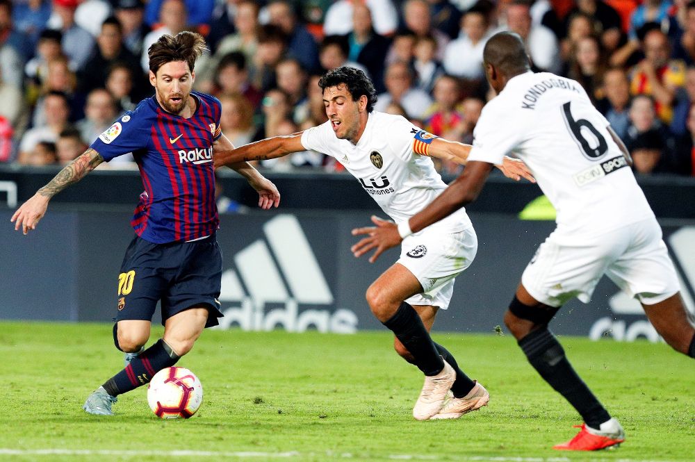 Dani Parejo (c) lucha por el balón ante el delantero argentino del FC Barcelona, Lionel Messi (i).